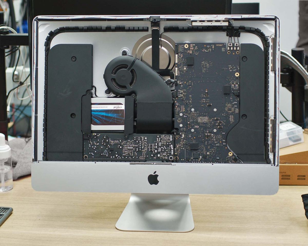 A 21.5-inch iMac with its display removed, showing the logic board, fan and drive bay
