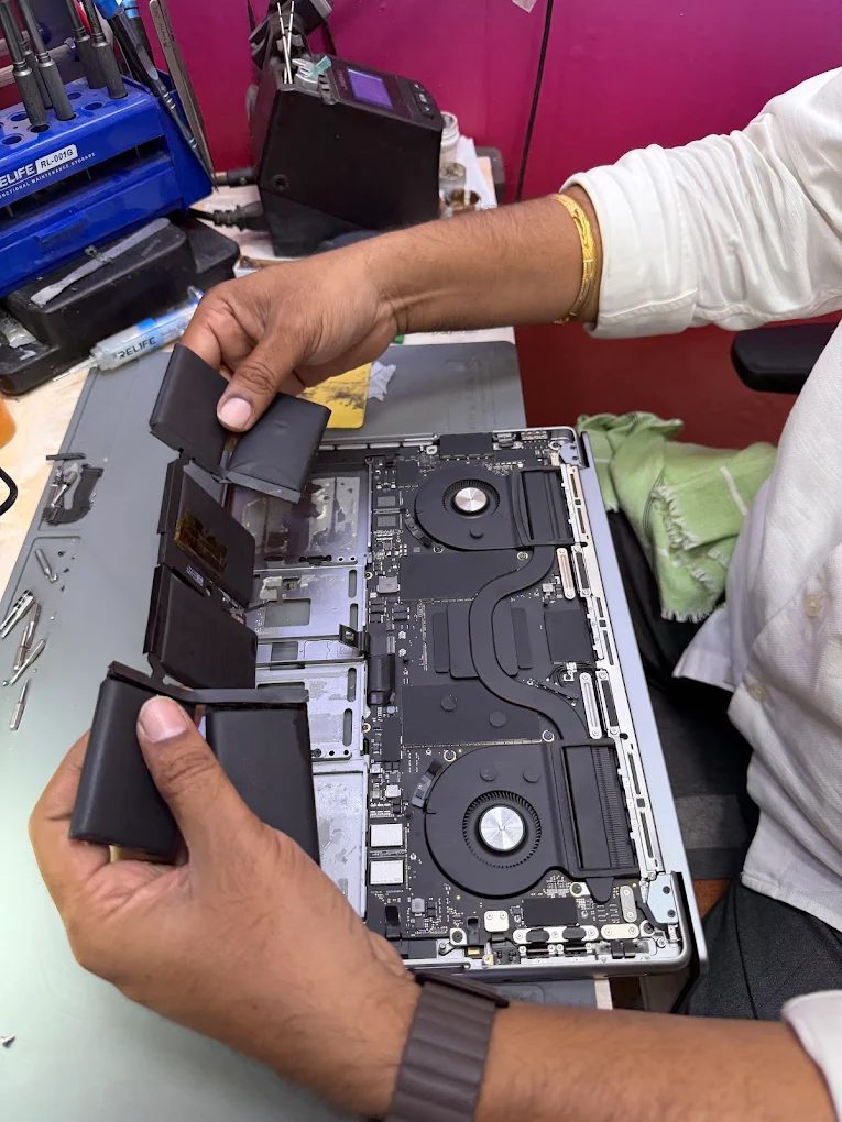 Battery cells being lifted out of an opened Apple Silicon MacBook Pro on the bench