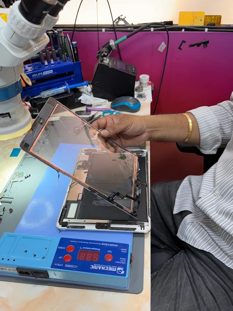 Cracked iPad glass being lifted away from the display on a heated separator plate